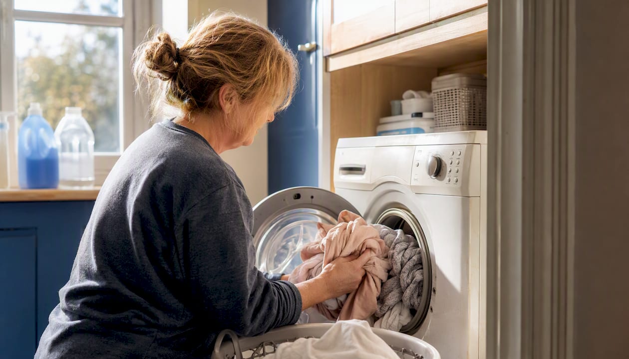 Hands loading laundry into washing machine