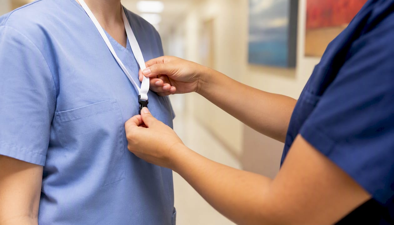 Hand placing badge lanyard on new healthcare worker